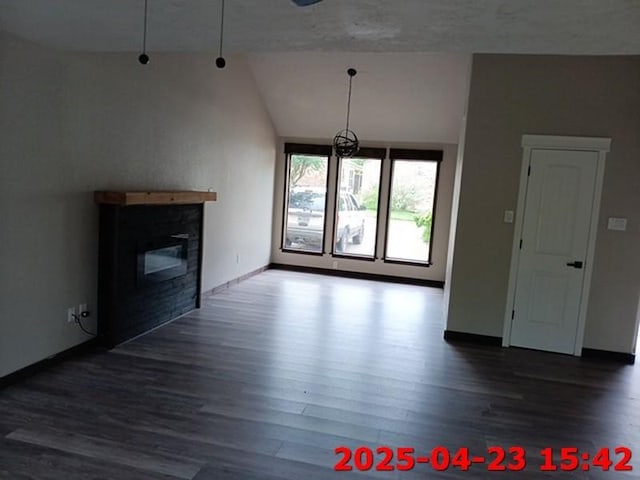 unfurnished living room featuring a glass covered fireplace, wood finished floors, vaulted ceiling, and baseboards