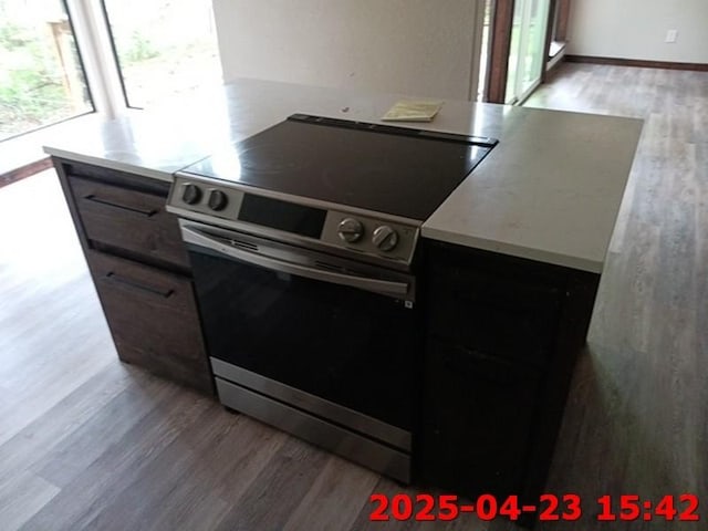 kitchen with light wood finished floors, electric stove, light countertops, and baseboards