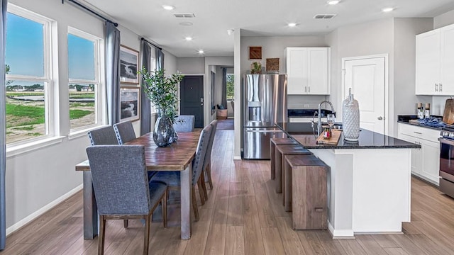 kitchen with visible vents, stainless steel appliances, light wood-style floors, and an island with sink