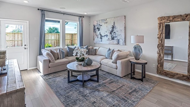 living area with recessed lighting, a wealth of natural light, wood finished floors, and baseboards