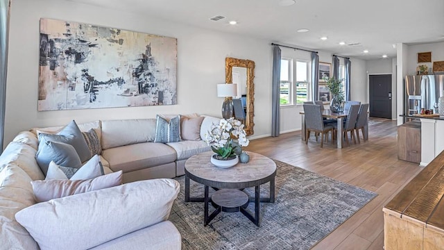 living area featuring wood finished floors, visible vents, recessed lighting, and baseboards