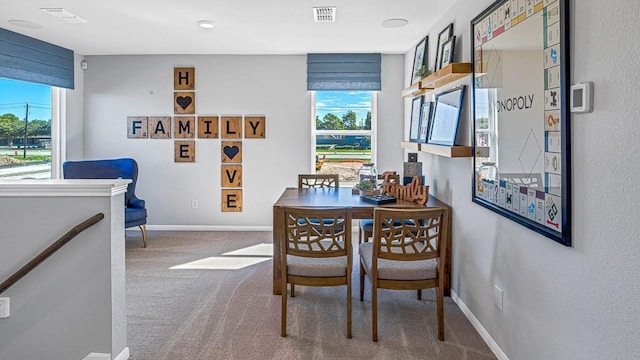 carpeted dining area featuring visible vents, a healthy amount of sunlight, and baseboards