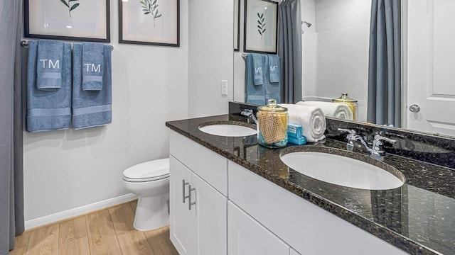 bathroom featuring wood finished floors, toilet, baseboards, and a sink