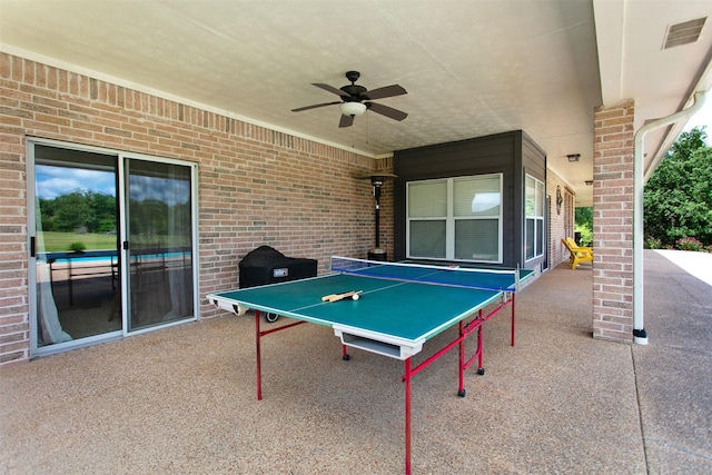 13671 Suzanne Pl, College Station, TX 77845 - rec room with visible vents, a wood stove, ceiling fan, and brick wall