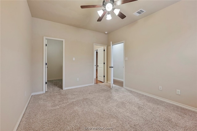 unfurnished bedroom with light colored carpet, ceiling fan, visible vents, baseboards, and a spacious closet