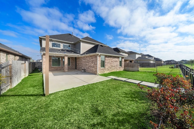 rear view of house featuring a lawn, a patio, brick siding, and a fenced backyard