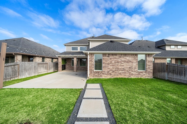 rear view of house with a shingled roof, a patio area, a fenced backyard, a lawn, and brick siding