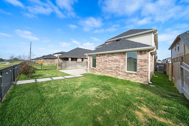 back of property featuring central AC, brick siding, a fenced backyard, and a yard