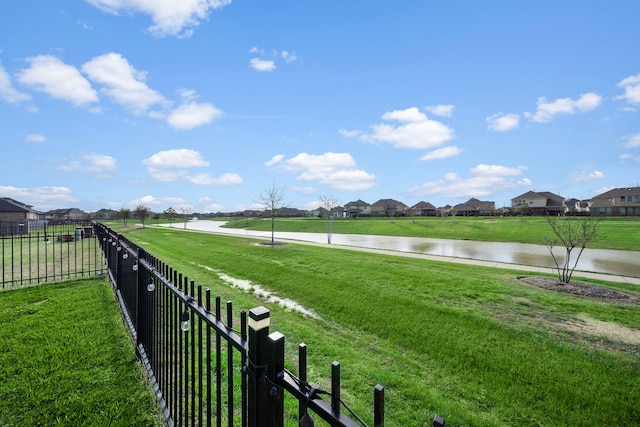 view of yard with fence, a residential view, and a water view