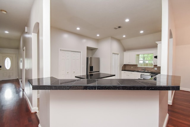 1802 Terry St, Houston, TX 77009 - kitchen featuring dark wood-style floors, stainless steel fridge, decorative backsplash, white cabinets, and recessed lighting