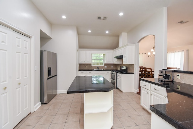 kitchen featuring under cabinet range hood, stainless steel appliances, tasteful backsplash, visible vents, and arched walkways