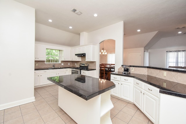 kitchen featuring lofted ceiling, visible vents, stainless steel gas range oven, and under cabinet range hood