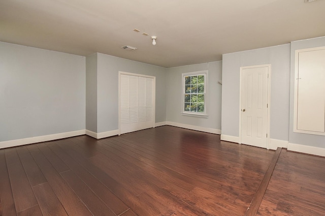 unfurnished room featuring visible vents, baseboards, and dark wood-type flooring