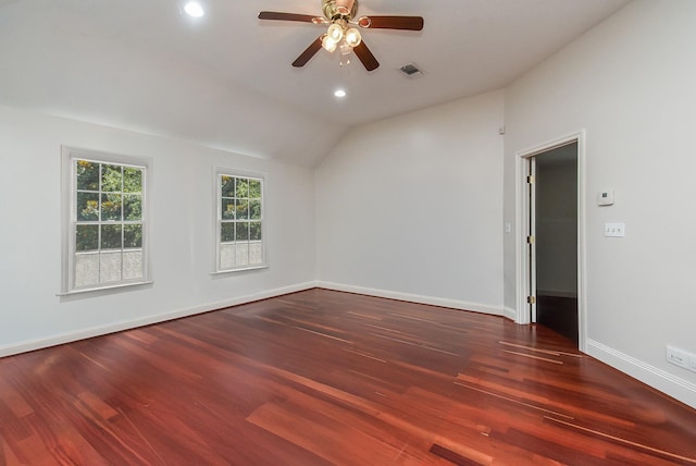 spare room with wood finished floors, vaulted ceiling, baseboards, visible vents, and a ceiling fan
