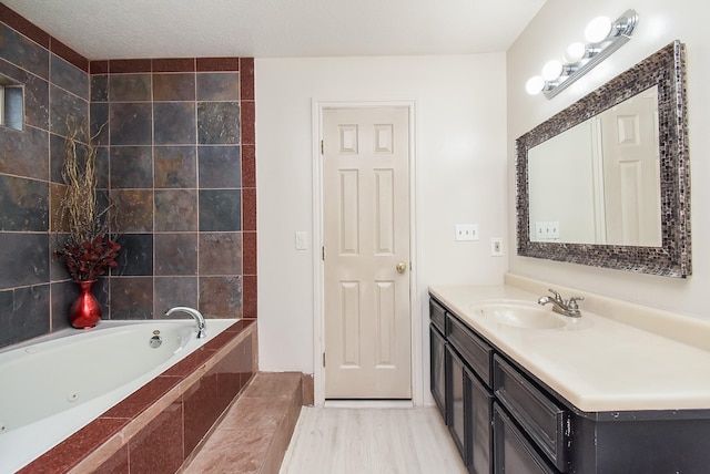 bathroom featuring a tub with jets, wood finished floors, and vanity