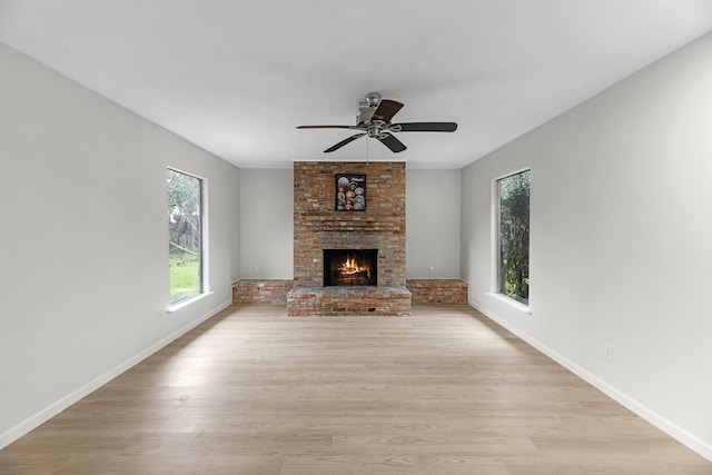 unfurnished living room featuring baseboards, a ceiling fan, light wood-style floors, and a fireplace