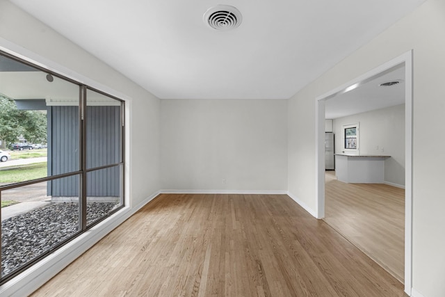 spare room with baseboards, visible vents, and wood finished floors