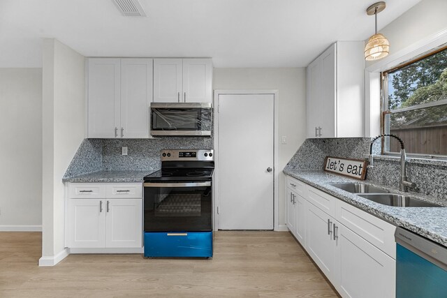 kitchen featuring a sink, decorative backsplash, light wood-style floors, visible vents, and appliances with stainless steel finishes