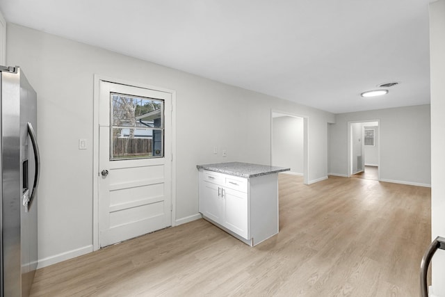 kitchen featuring stainless steel refrigerator with ice dispenser, a peninsula, light wood finished floors, and baseboards