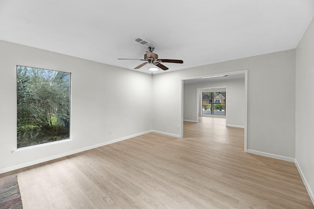 empty room with baseboards, visible vents, ceiling fan, and light wood-style floors
