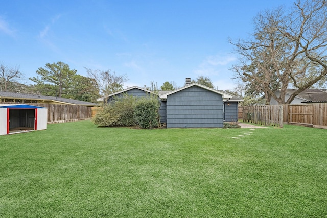 view of yard featuring an outdoor structure, a storage unit, and a fenced backyard