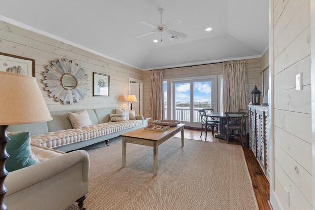 living room featuring ceiling fan, a water view, wood-type flooring, wooden walls, and recessed lighting