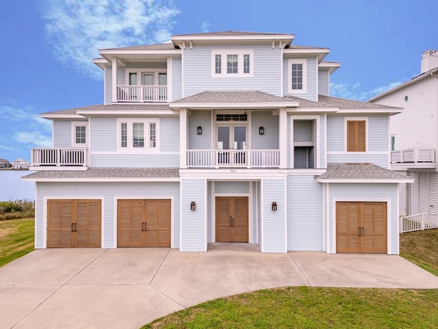 coastal home featuring driveway, a balcony, a shingled roof, and an attached garage