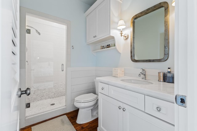 bathroom featuring a stall shower, toilet, tile walls, wood finished floors, and vanity
