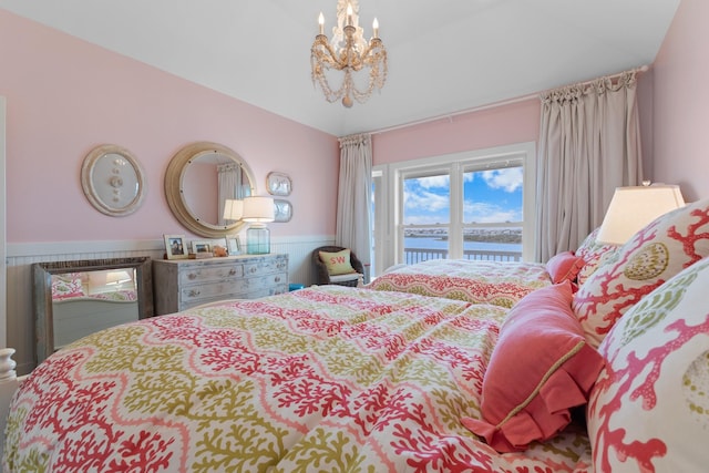 bedroom featuring an inviting chandelier, a water view, a wainscoted wall, access to exterior, and vaulted ceiling