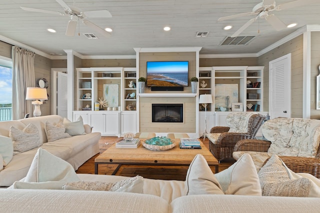 living area featuring visible vents, ornamental molding, a ceiling fan, and wood finished floors