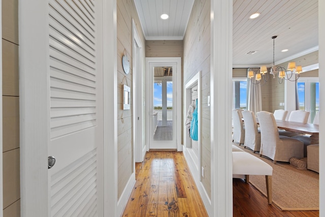 corridor with a chandelier, recessed lighting, crown molding, and wood-type flooring