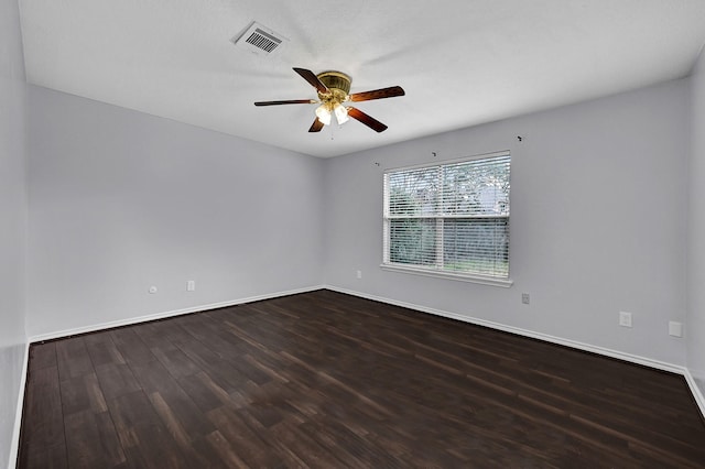 spare room with dark wood-style floors, ceiling fan, baseboards, and visible vents