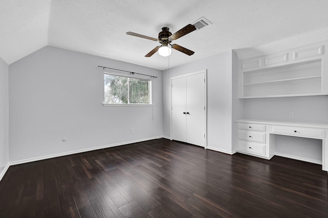unfurnished bedroom featuring lofted ceiling, visible vents, dark wood-style floors, a closet, and built in study area