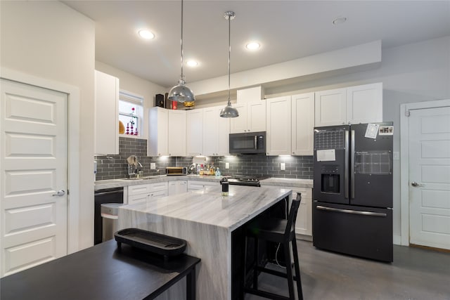 kitchen featuring tasteful backsplash, white cabinets, black appliances, a kitchen bar, and decorative light fixtures