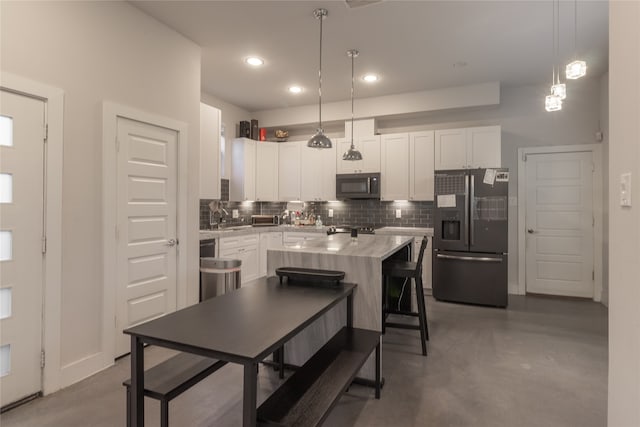 kitchen with decorative backsplash, stainless steel fridge, concrete floors, black microwave, and white cabinets