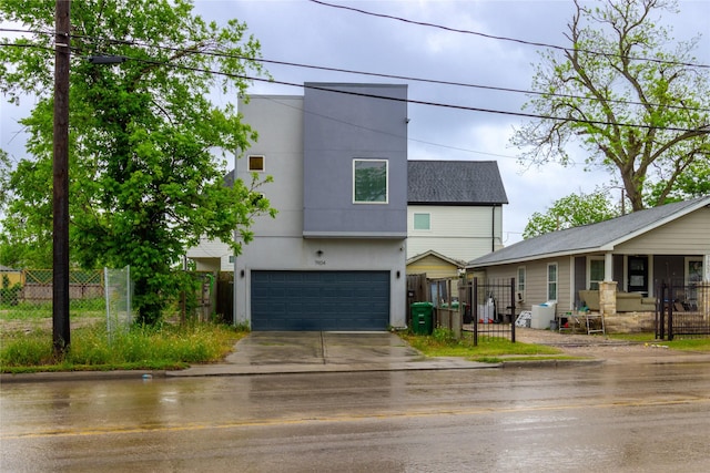 contemporary house with an attached garage, a gate, driveway, stucco siding, and fence