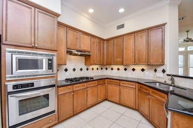 kitchen featuring brown cabinets, a sink, under cabinet range hood, visible vents, and appliances with stainless steel finishes
