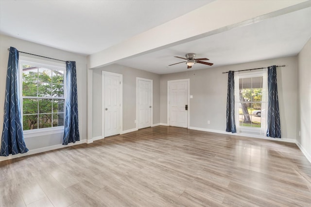 unfurnished room with light wood finished floors, baseboards, and plenty of natural light