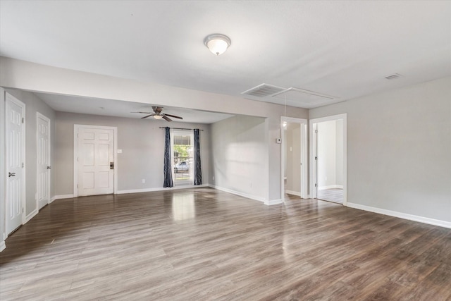 unfurnished living room featuring wood finished floors, attic access, baseboards, visible vents, and a ceiling fan