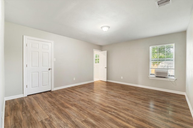 empty room with visible vents, a wealth of natural light, and wood finished floors