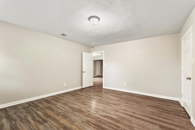 unfurnished bedroom with visible vents, dark wood-style flooring, and baseboards