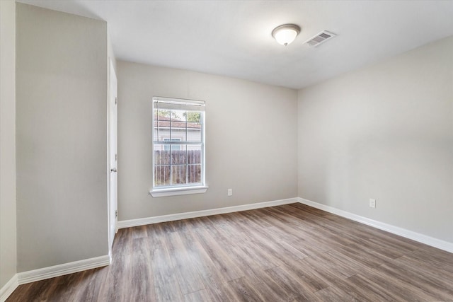 empty room with baseboards, visible vents, and dark wood-style flooring