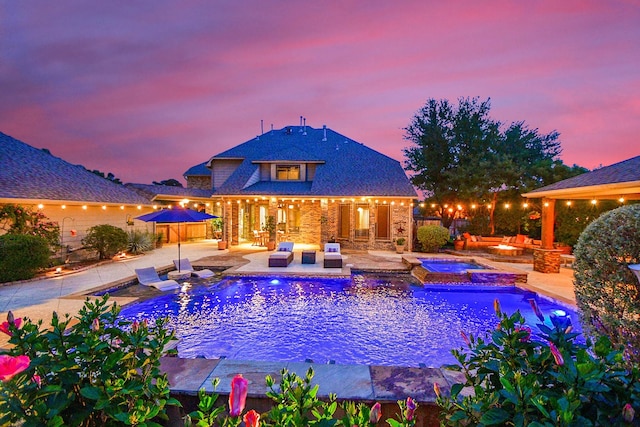 pool at dusk featuring an in ground hot tub, an outdoor living space, an outdoor pool, and a patio area