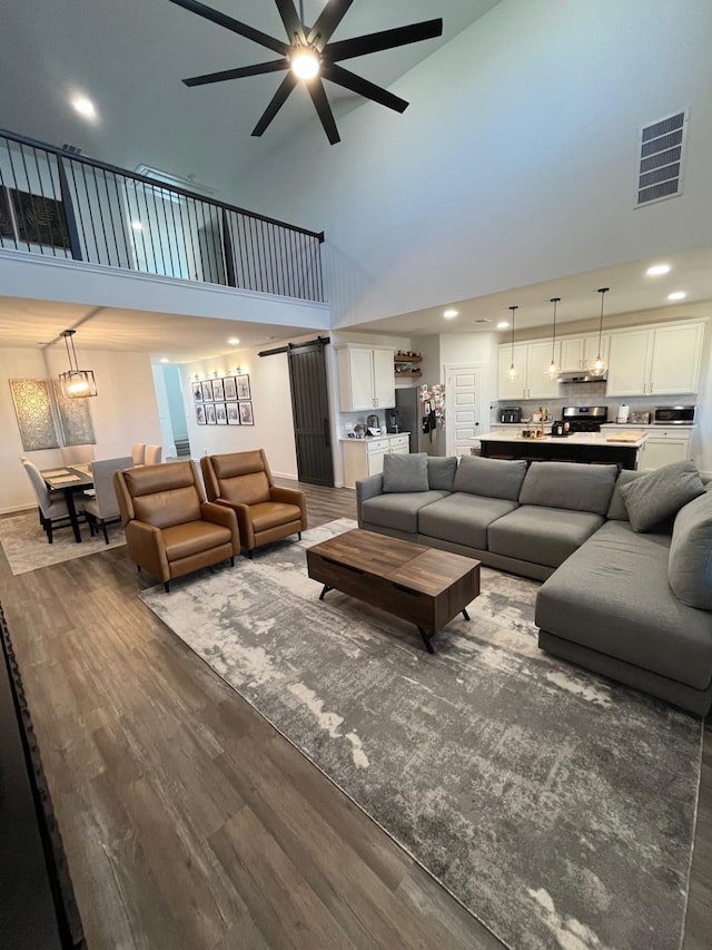 living room with recessed lighting, wood finished floors, visible vents, a ceiling fan, and a high ceiling