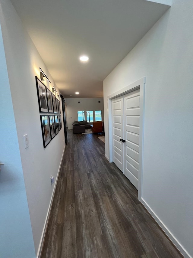 hallway with baseboards, recessed lighting, and dark wood-type flooring