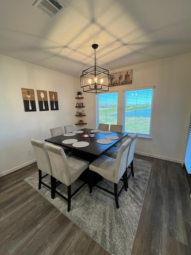 dining space with wood finished floors, visible vents, a chandelier, and baseboards