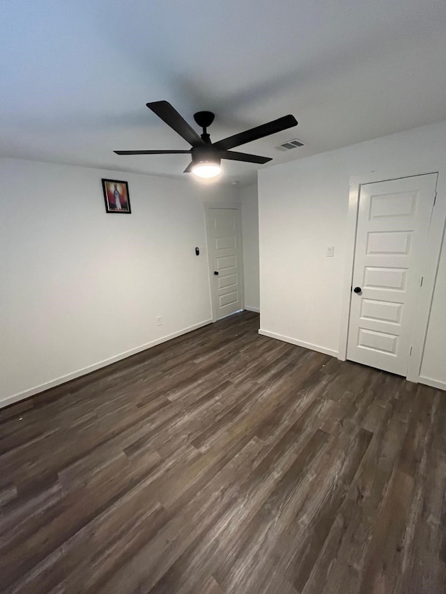 unfurnished room featuring dark wood finished floors, visible vents, ceiling fan, and baseboards
