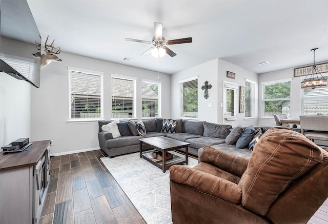 living room featuring wood tiled floor, ceiling fan, and a healthy amount of sunlight