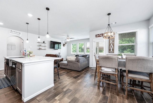 kitchen with a kitchen bar, visible vents, light countertops, hanging light fixtures, and dark wood finished floors