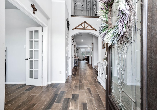 foyer entrance featuring dark wood-type flooring, french doors, baseboards, and arched walkways